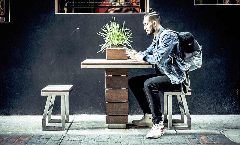 millennial sitting on bench at a restaurant