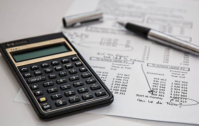 calculator and pen on investment return calculation sheet