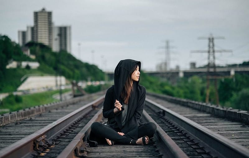 risky woman sitting on train tracks